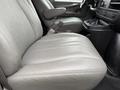 A gray leather bench seat inside a 2014 GMC Savana with armrests and cup holders visible in the foreground