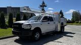 A white 2019 RAM 3500 truck with a utility body and an extended lift platform attached to the bed