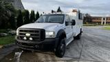 A 2007 Ford F-550 with a white exterior and a utility body featuring multiple lights on the roof and fog lights on the front grille