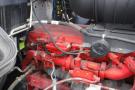 Red engine components of a 2015 Kenworth T660 visible with various hoses wires and mechanical parts