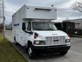 A 2006 GMC C5000 box truck with a white exterior and blue stripes parked on a street