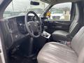 Interior view of a 2014 Chevrolet Express featuring a driver's seat and passenger seat with grey upholstery and a dashboard displaying various controls and instruments