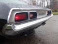 A close-up view of the rear of a 1974 Dodge Challenger featuring chrome trim and red taillights with raindrops on the surface