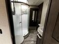 Interior view of a bathroom featuring a circular shower stall with glass doors a sink with a countertop and dark cabinetry