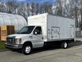 A white 2013 Ford Econoline truck with a boxy cargo area and a flat front design parked on a street