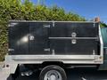 A 2008 Ford F-550 truck with a silver metal flatbed featuring two black storage boxes with locking mechanisms mounted on the rear of the truck