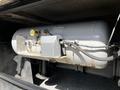A gray propane tank with visible valves and connections mounted in a compartment of a 2000 Ford Motorhome