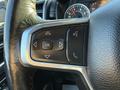 A close-up of the steering wheel controls of a 2023 RAM 3500 featuring buttons for navigation volume and phone functions