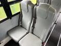 Two grey seats with seat belts inside a vehicle designed for transporting passengers