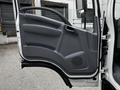 The image shows the open driver's side door of a 2018 Isuzu NPR featuring a gray interior panel and a black handle