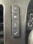 Control panel of a 2013 Chevrolet Express featuring three buttons for lights vehicle information and a checkbox with a checkmark