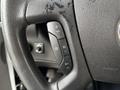 A close-up of a steering wheel control panel from a 2020 Chevrolet Express featuring buttons for cruise control settings and other functions