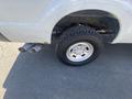 A white 2016 Ford F-350 SD with a silver wheel and a black tire showing dual exhaust pipes beneath the rear wheel