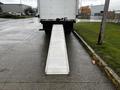 A 2021 Mitsubishi FE truck with a metallic loading ramp extended from the rear