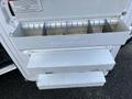 A set of three metal storage drawers with a white finish mounted on a vehicle door, showcasing a slightly worn appearance and a label area on the front