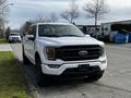 A 2021 Ford F-150 in white parked on the side of the road showcasing its modern design and distinctive front grille