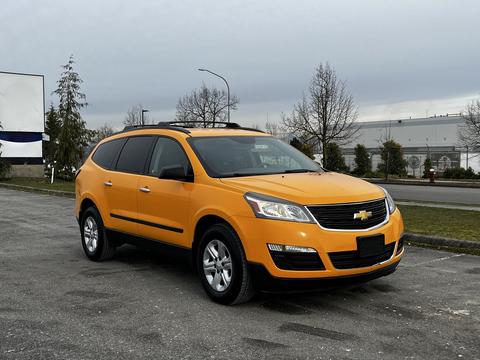 A 2015 Chevrolet Traverse in bright orange parked in an outdoor setting with four doors and a large grille