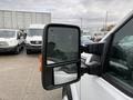 A 2013 Ford F-350 SD side mirror reflecting an image and featuring a black frame and orange reflector