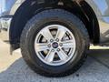 A close-up of a silver alloy wheel from a 2018 Ford F-150 featuring a rugged tire with aggressive tread design