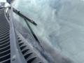 A close-up view of a 2010 Ford Econoline windshield featuring a wiper blade and minor scratches on the glass surface