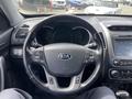 Steering wheel of a 2015 Kia Sorento featuring the Kia logo with control buttons for audio and cruise settings