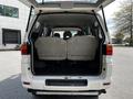 A white 2003 Mitsubishi 7 Passenger Van with open rear doors revealing two rows of gray upholstered seats inside