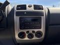 Dashboard of a 2011 Chevrolet Colorado featuring controls for audio and climate with buttons and knobs in a silver and black design