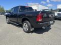 A black 2011 RAM 1500 pickup truck with a crew cab and chrome accents parked on a gravel surface