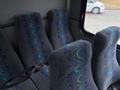 Interior seating of a 2020 Chevrolet Express showing row of grey fabric seats with blue and teal wave patterns and seat belts