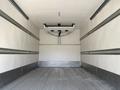 Interior view of a 2023 Ford E-450 cargo space with white walls and metal tracks on the sides for securing loads