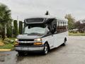 A 2019 Chevrolet Express shuttle bus with a black front and white body parked at an angle showcasing its large windshield and side windows