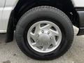 A silver alloy wheel on a 2011 Ford Econoline with a black tire displaying the brand name and tire specifications