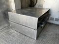 A silver metal storage compartment with two stacked drawers inside a vehicle's cargo area