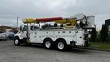 A white 2006 International 7500 bucket truck with an extended yellow and red boom and a bucket attachment on the side