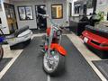 2024 Harley Davidson Fat Boy with a chrome engine and a bold red paint job positioned prominently in a showroom setting