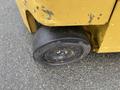 Close-up of a worn black rubber wheel from a yellow Hyster S80XLBCS forklift showing scratches and markings on the surface