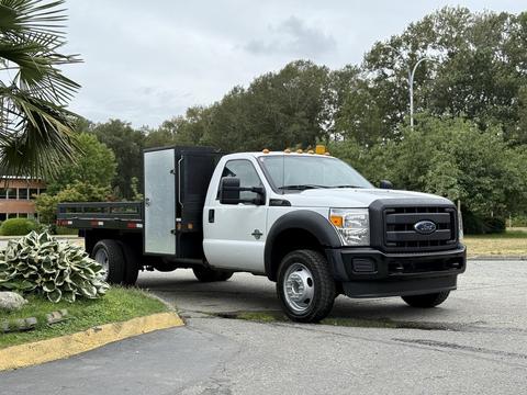 A 2016 Ford F-550 truck with an open flatbed and a black storage compartment attached to the side