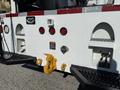 A rear view of a 2010 International 4300 truck with red taillights a yellow hitch and various control ports on a white surface