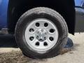 Close-up of a silver wheel with five spokes and a Chevrolet logo at the center mounted on a black tire with a tread pattern visible