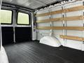 Interior of a 2023 GMC Savana van with wooden shelves along the walls and a rubber flooring surface
