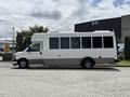 A 2020 Chevrolet Express passenger bus with a white exterior and large windows is parked on a paved surface