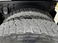 Close-up of a large, rugged tire with deep treads mounted on a vehicle, showcasing wear and dirt on the surface