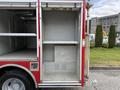A 2007 Ford F-550 fire truck with an open side compartment showing empty shelves and a metal panel at the bottom