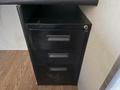 A black three-drawer filing cabinet with a sleek design and a keyhole on the side
