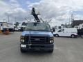 A blue 2010 Ford Econoline van with a raised aerial lift mechanism mounted on top facing forward