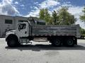 A 2010 Freightliner M2 106 dump truck with a silver metal bed and a white cab parked in a lot