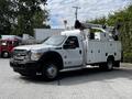 A 2016 Ford F-550 utility truck with a white body and orange lights mounted on the roof it features a bucket lift attached to the rear of the truck
