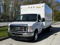 A 2019 Ford Econoline box truck with a white cargo box and a silver front grille parked on a street