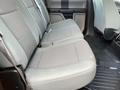 A rear seat view of a 2017 Ford F-250 SD featuring gray fabric upholstery with a bench seat design and rubber floor mat with a textured surface