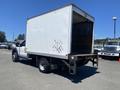 A white 2015 Ford F-450 SD with a box truck body and an open rear loading area is parked with its back facing the viewer